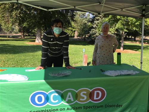 A man and a woman stand behind an information table at a resource fair